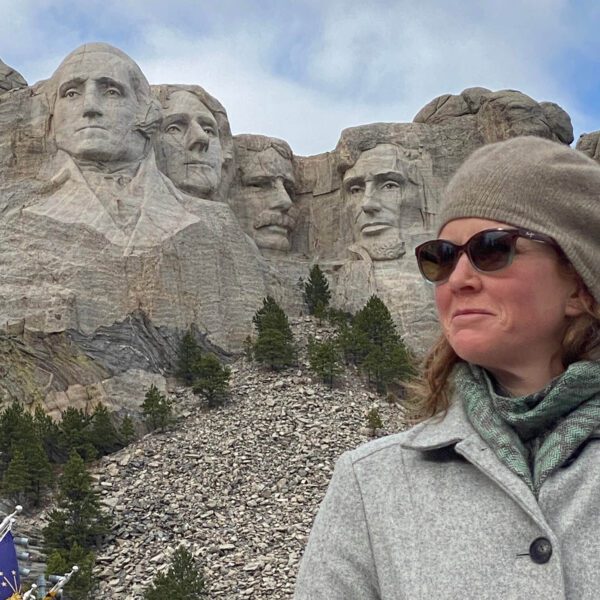 A woman poses alongside Mount Rushmore.