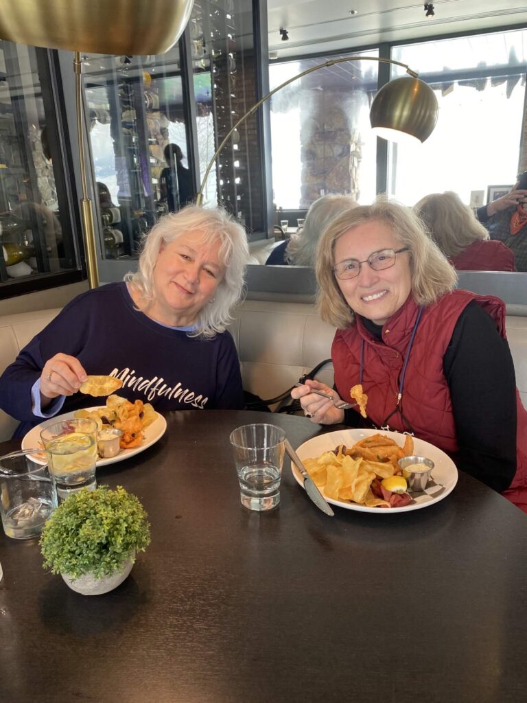 Two friends enjoy a lunch of trout and chips at Palate Restaurant in the National Museum of Wildlife Art. Taken on a Teton Excursions private winter tour of Grand Teton National Park.