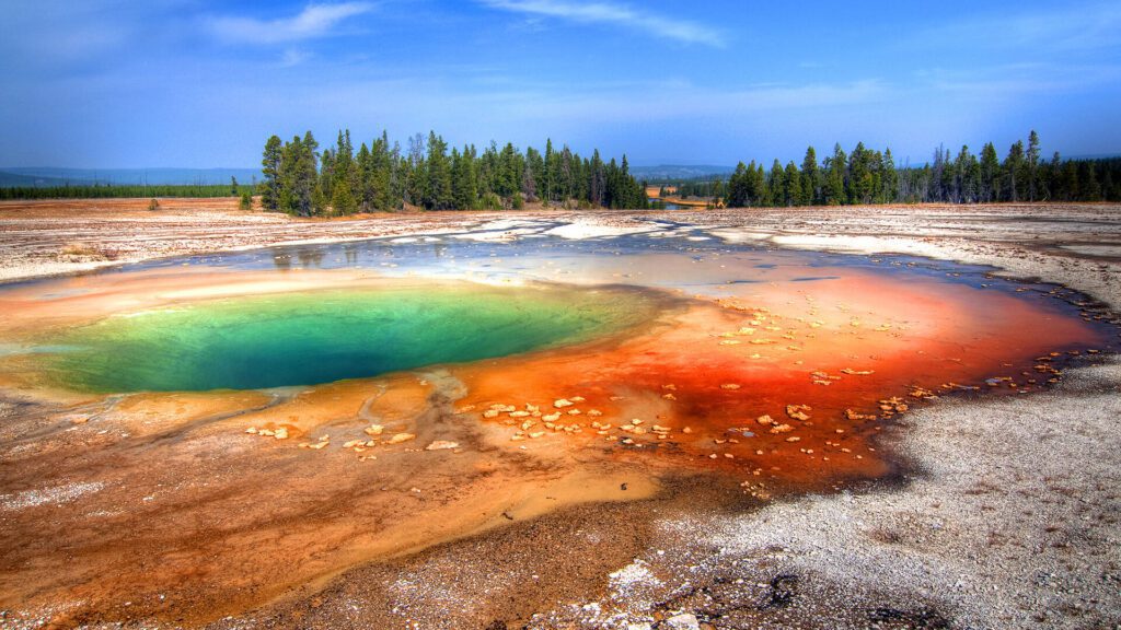 Hot Spring pool in Yellowstone National Park. A couple watches as Old Faithful geyser erupts in Yellowstone National Park. Taken on a Teton Excursions tour of Yellowstone National Park.