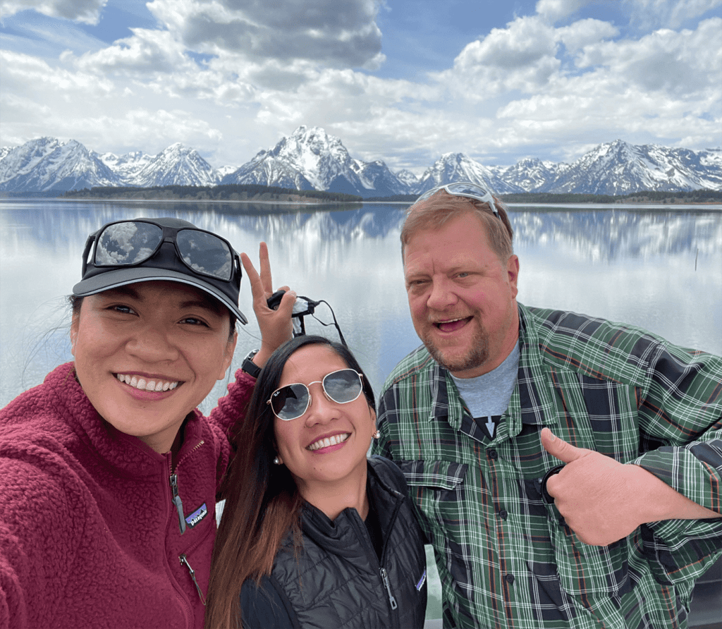 Three friends posing in front of the Teton Mountains at Jackson Lake, taken on a Teton Excursions tour to Grand Teton National Park