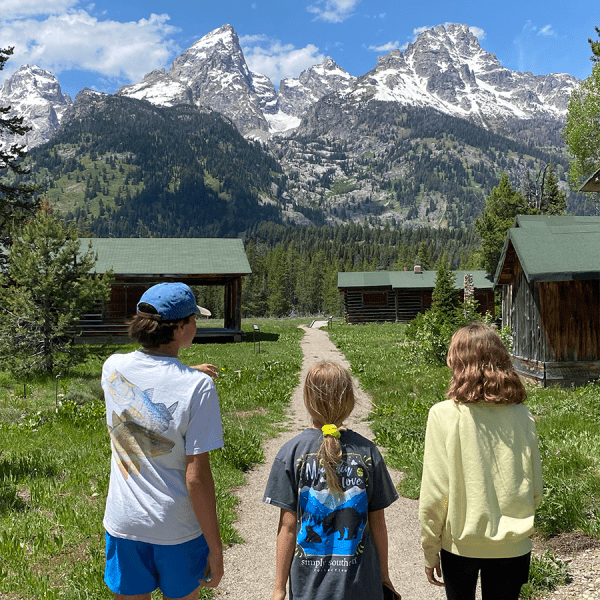 Three adolescents walk toward the towering Grand Teton mountains. Near Geraldine Lucas's homestead. Taken on a Teton Excursions tour to Grand Teton National Park