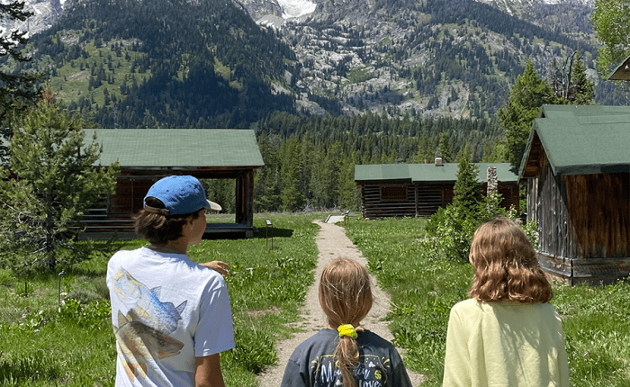 Three adolescents walk toward the towering Grand Teton mountains. Near Geraldine Lucas's homestead. Taken on a Teton Excursions tour to Grand Teton National Park
