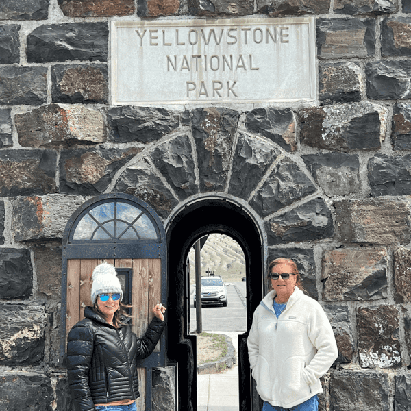 Mother and daughter in front of the Roosevelt Arch in Yellowstone National Park, near Gardiner, MT. taken on a Teton Excursions tour to Yellowstone National Park