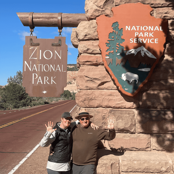 Couple in front of the entrance sign to Zion National Park. Taken on a Teton Excursions tour to Utah's Mighty 5 National Parks
