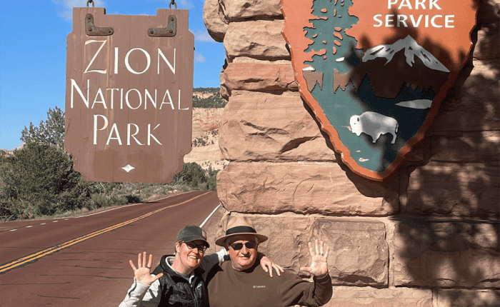 Couple in front of the entrance sign to Zion National Park. Taken on a Teton Excursions tour to Utah's Mighty 5 National Parks